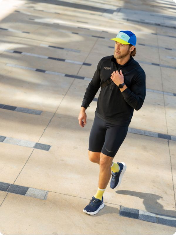 Man walking wearing HOKA shoes and apparel.